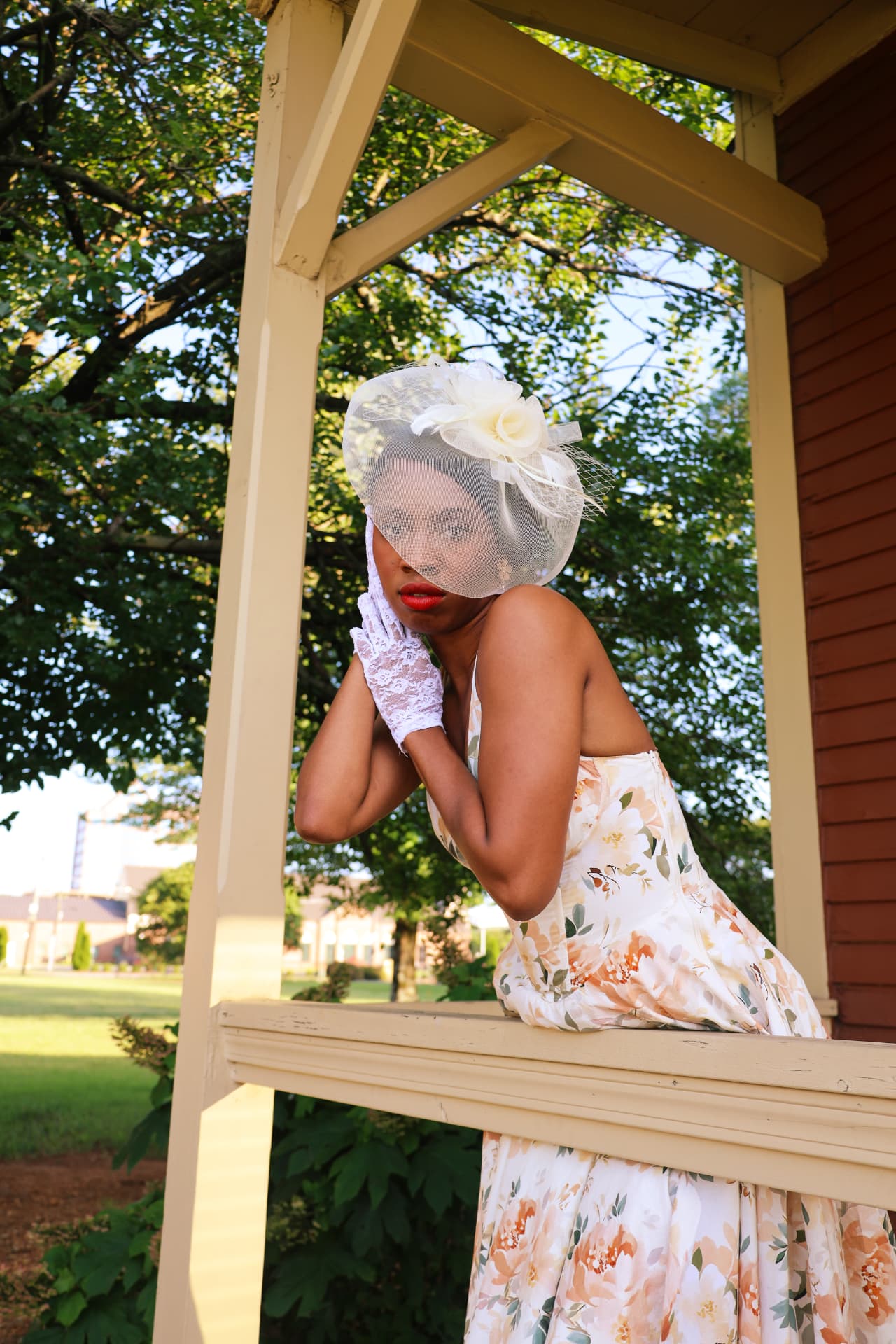Vintage floral dress portrait with birdcage veil and lace gloves on a porch