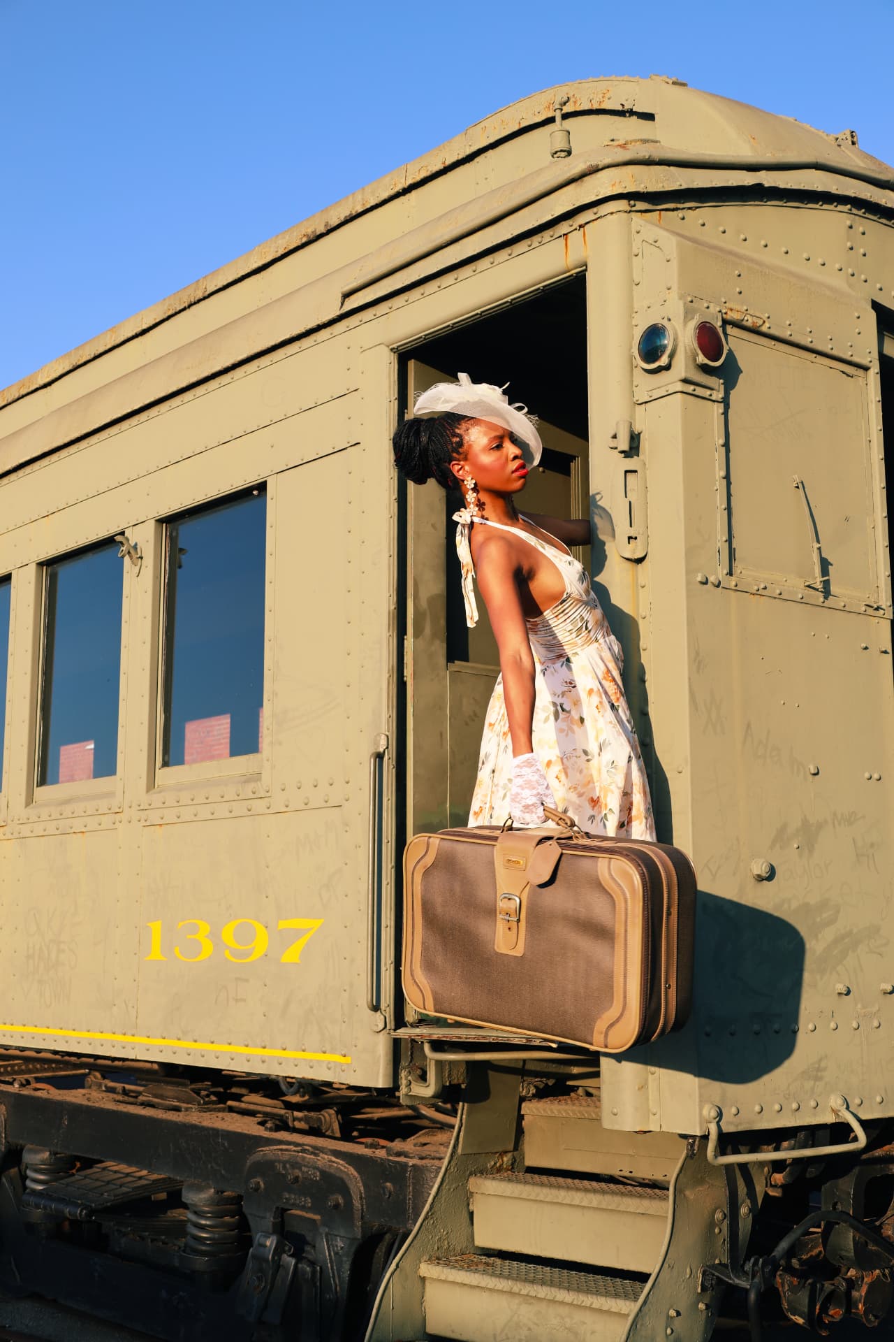 Profile portrait of a model with a suitcase framed in a vintage rail car doorway