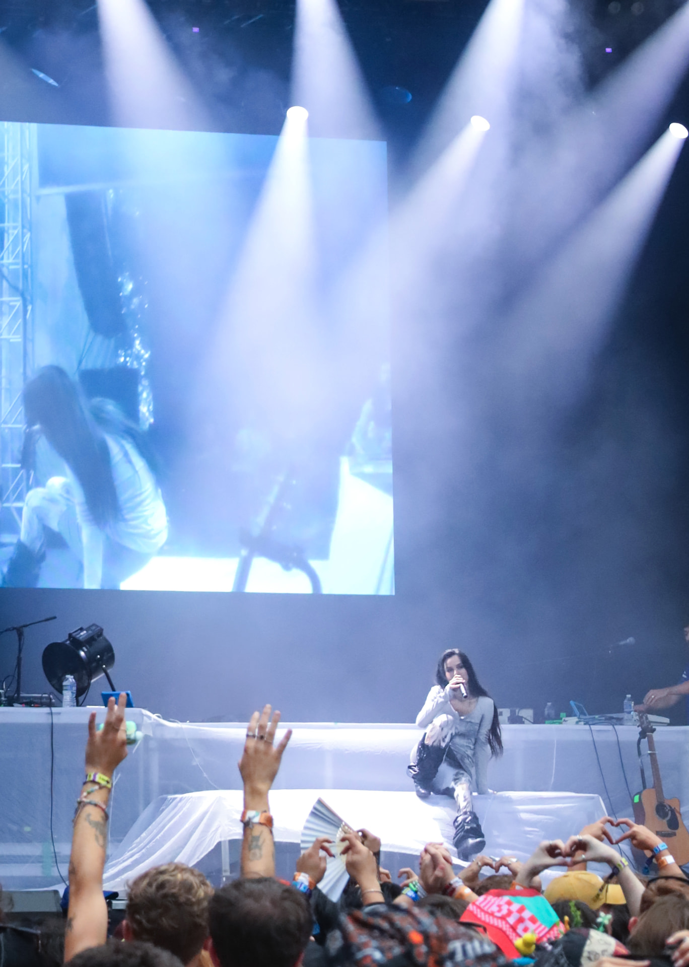 Performer seated at the stage edge under spotlights and haze