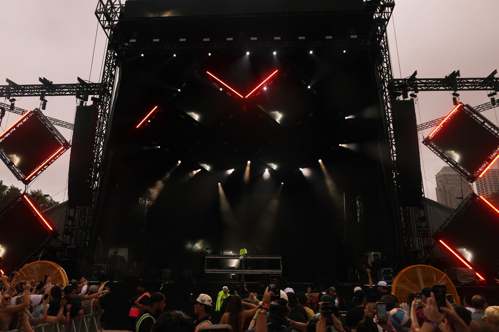 Wide dusk view of the main stage with red neon lights and crowd
