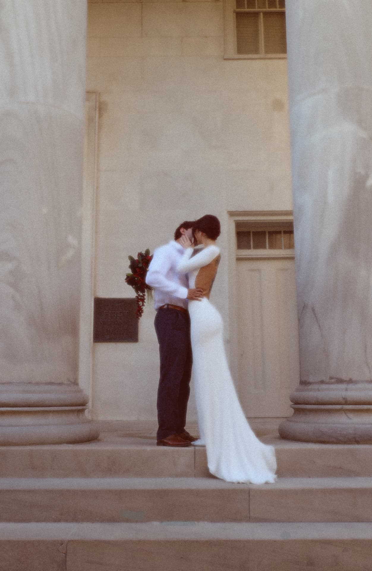 Couple sharing a kiss on the steps between grand stone pillars