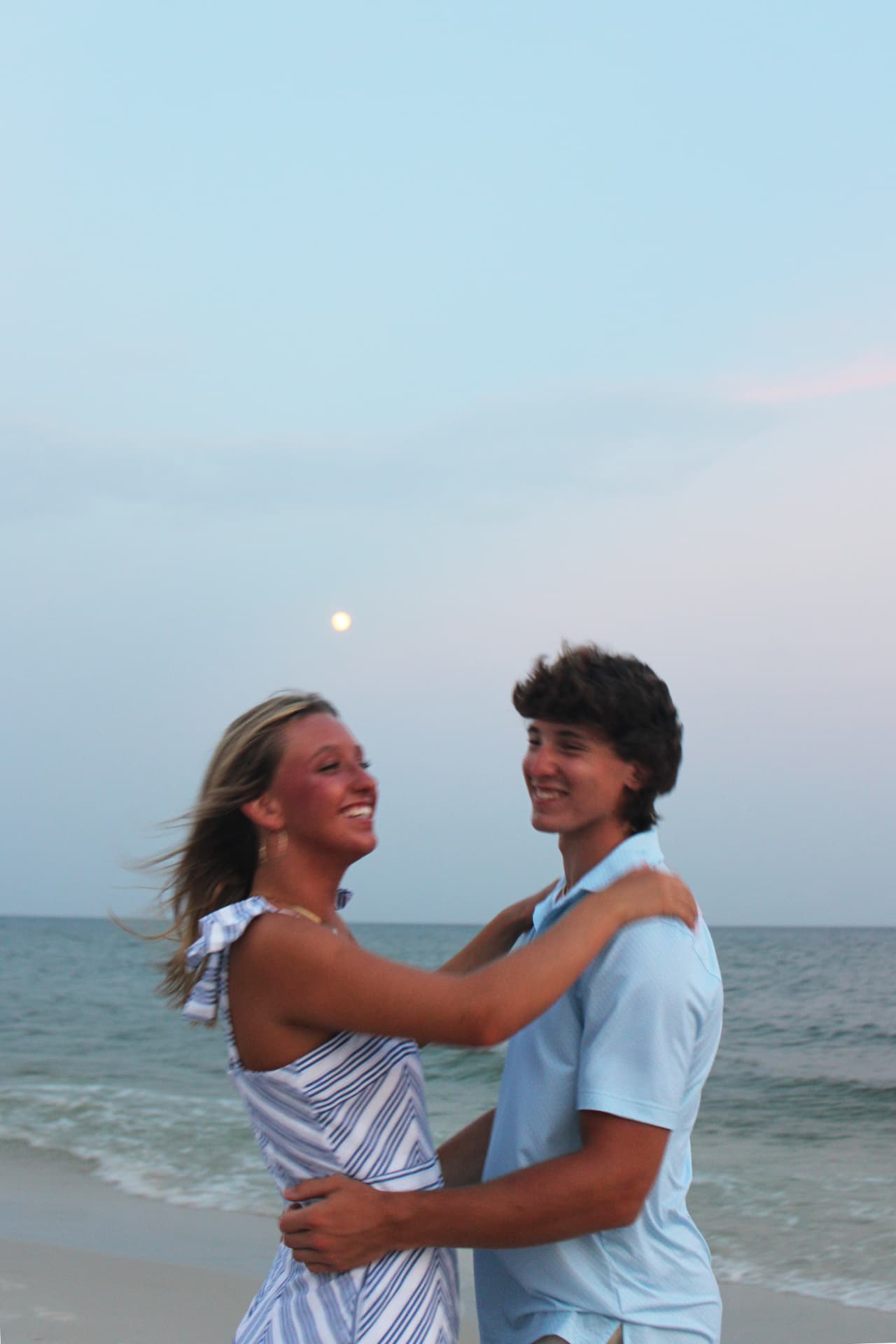 Couple laughing in a close embrace at dusk on the beach