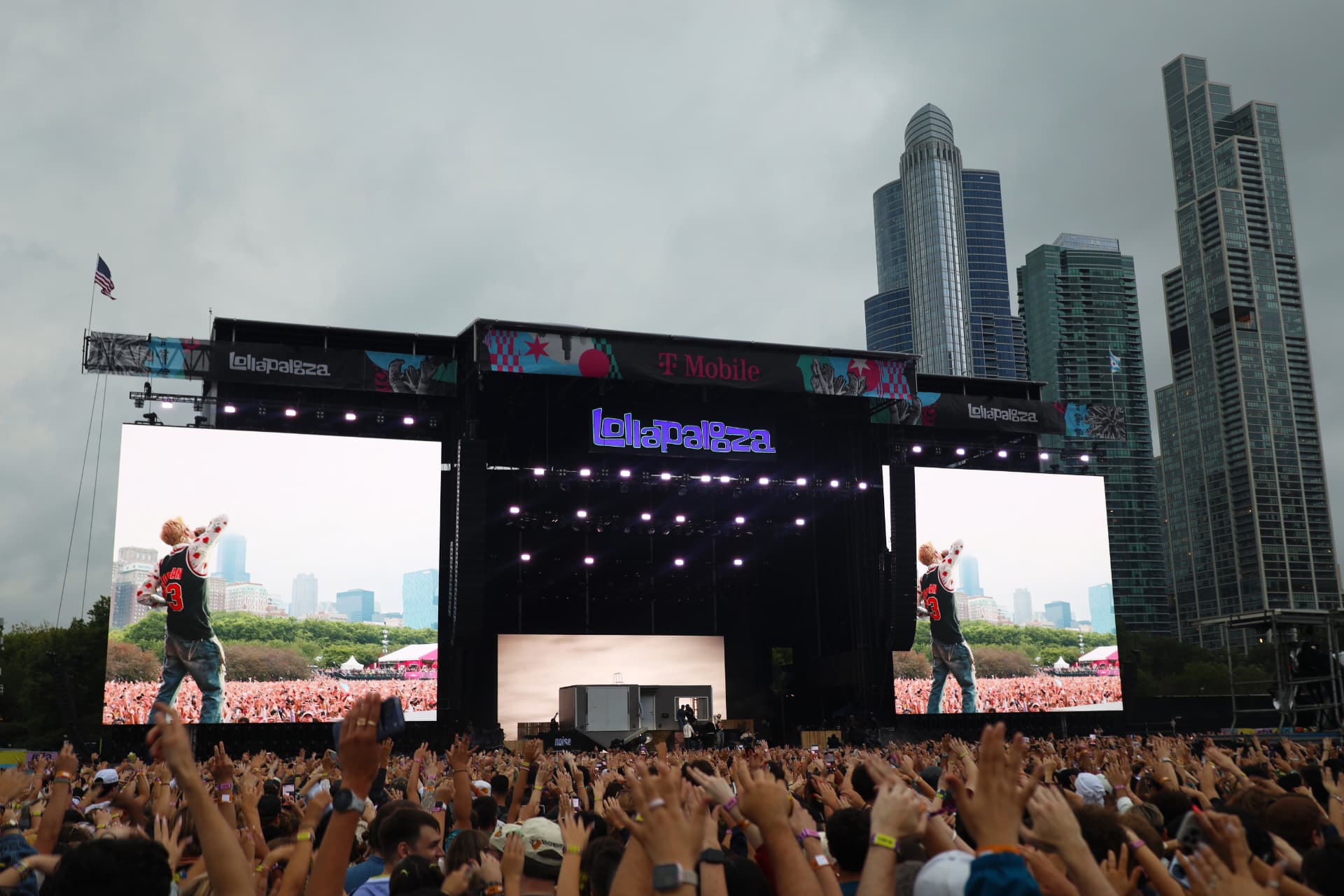 Lollapalooza main stage with performer on massive screens and the Chicago skyline behind