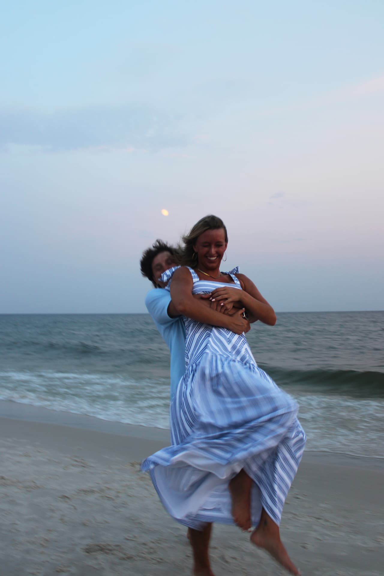 Couple laughing as he hugs her from behind in the surf