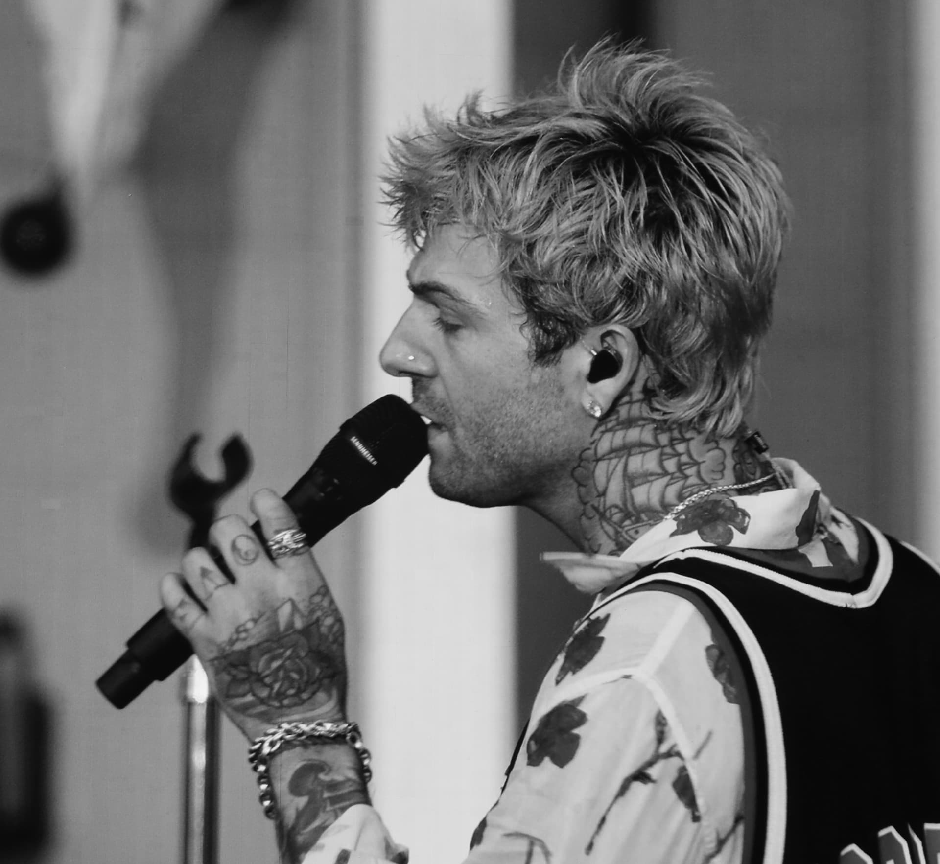 Black and white profile of a tattooed vocalist singing into a microphone
