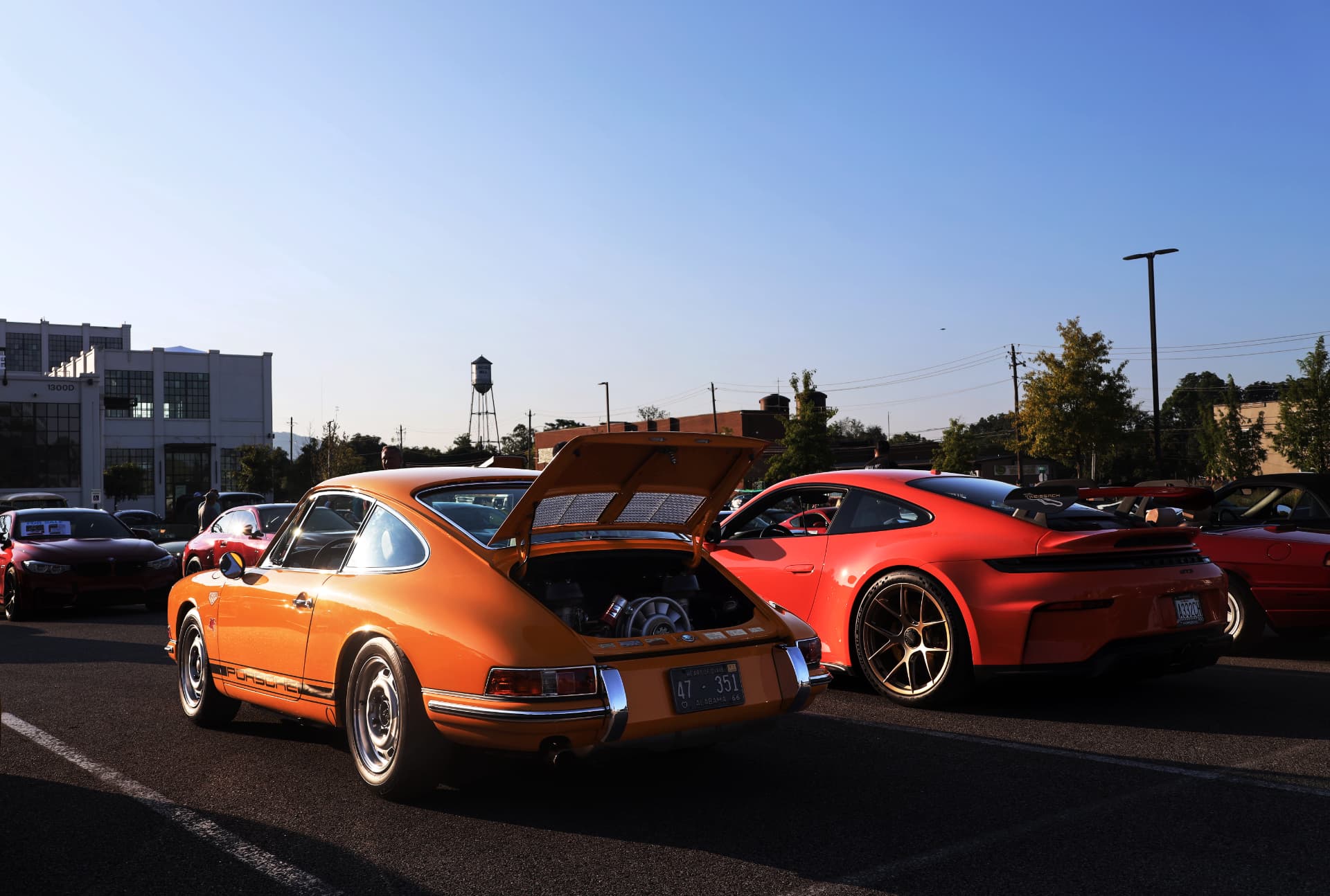 Classic orange Porsche 911 with open rear engine cover beside a red GT3 at a cars and coffee