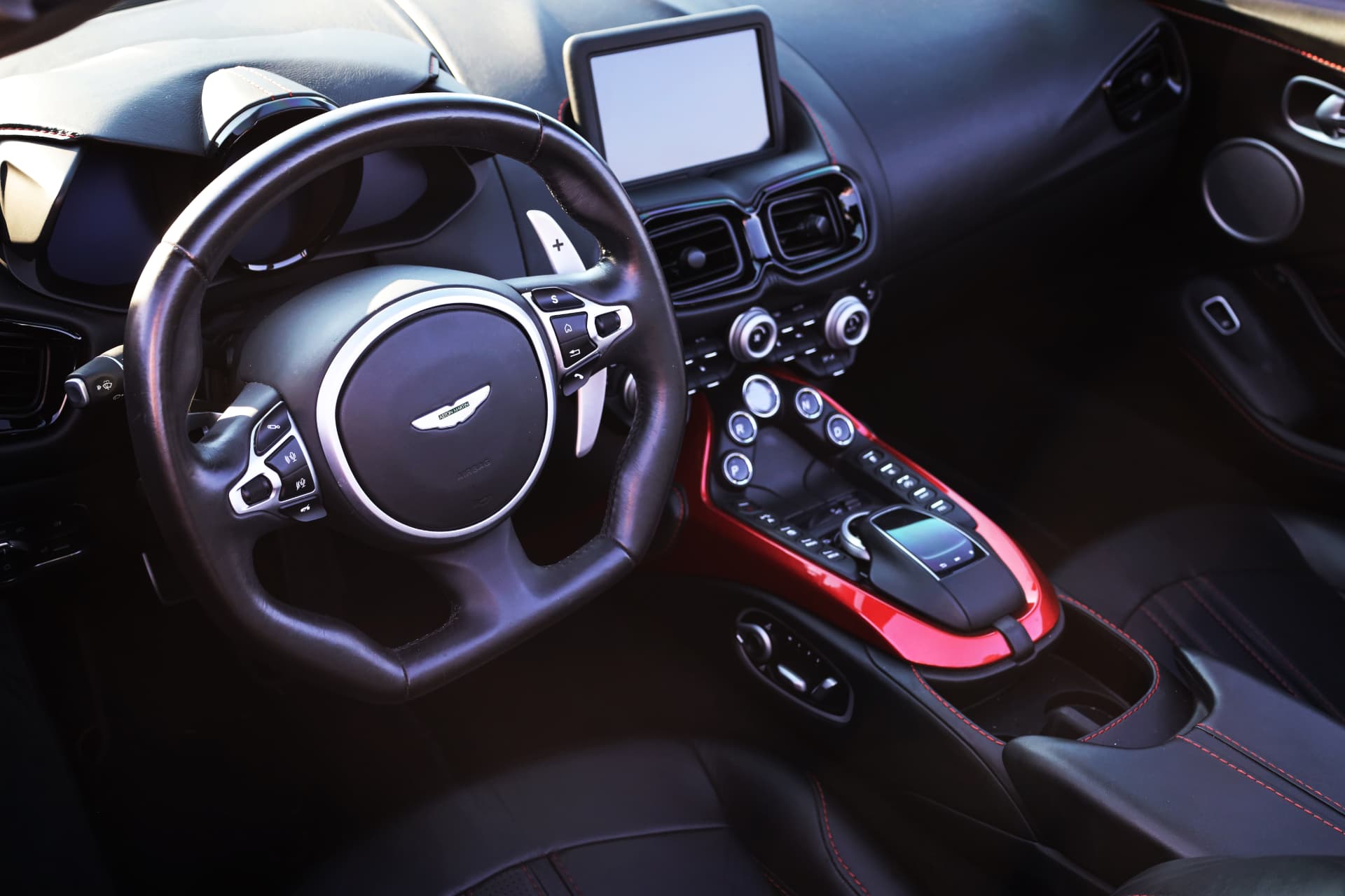 Aston Martin Vantage cockpit with leather steering wheel, red center console and infotainment screen