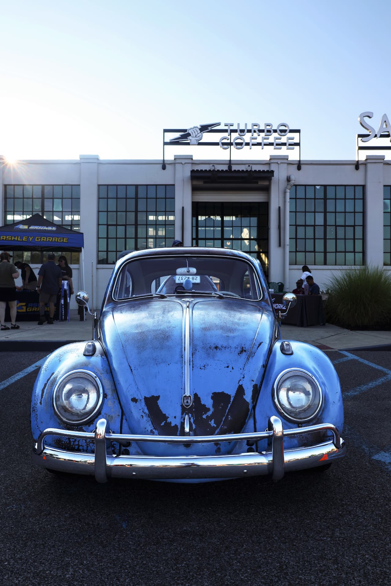 Weathered blue Volkswagen Beetle parked in front of Turbo Coffee
