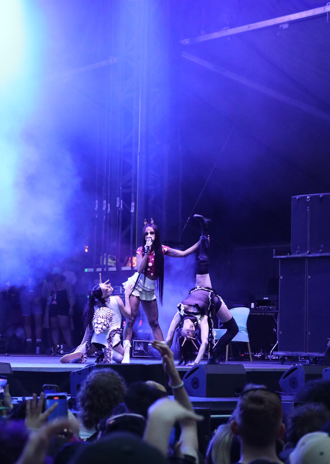 Vocalist and dancers mid performance in purple haze above the crowd