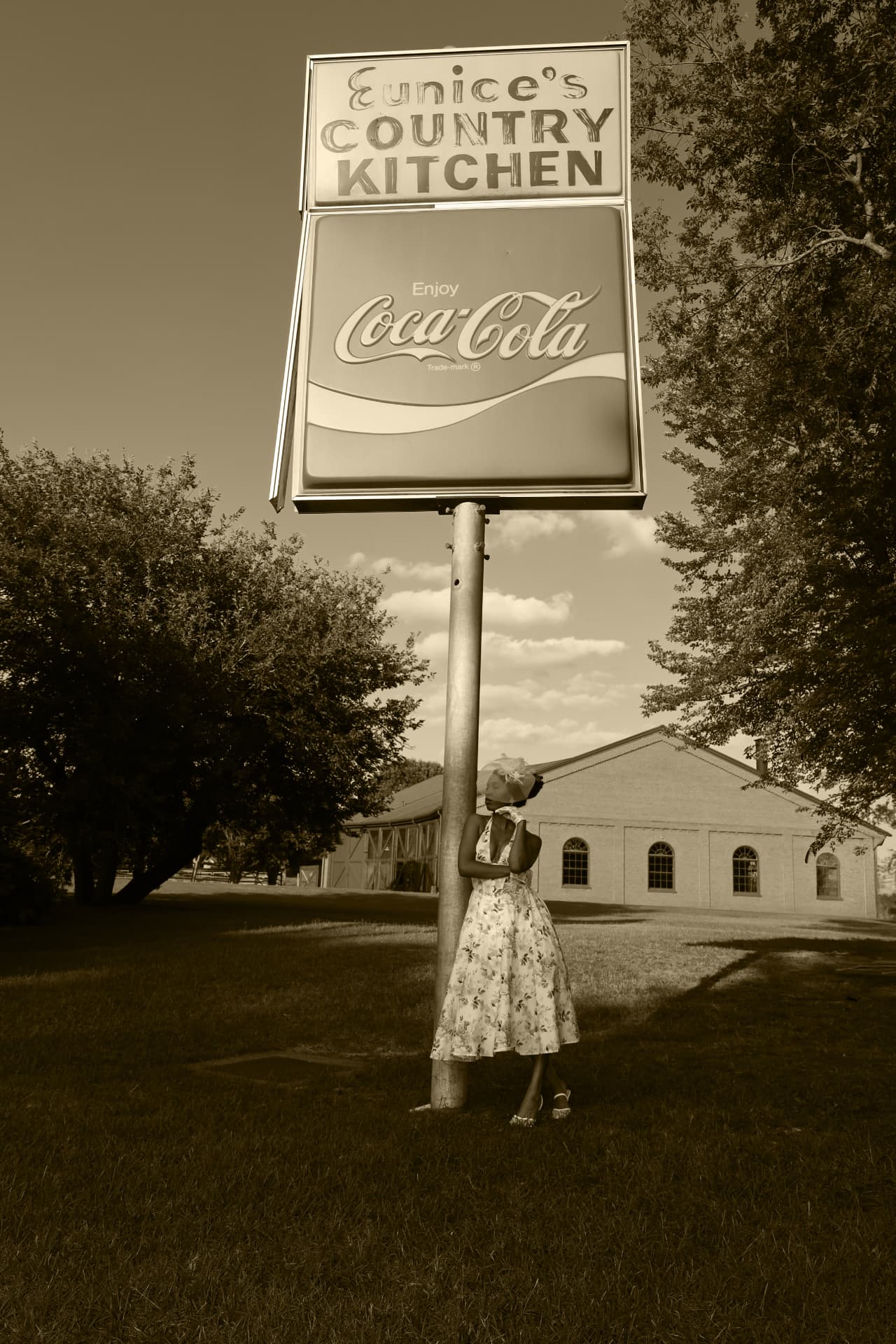 Sepia vintage portrait leaning against a country kitchen roadside sign