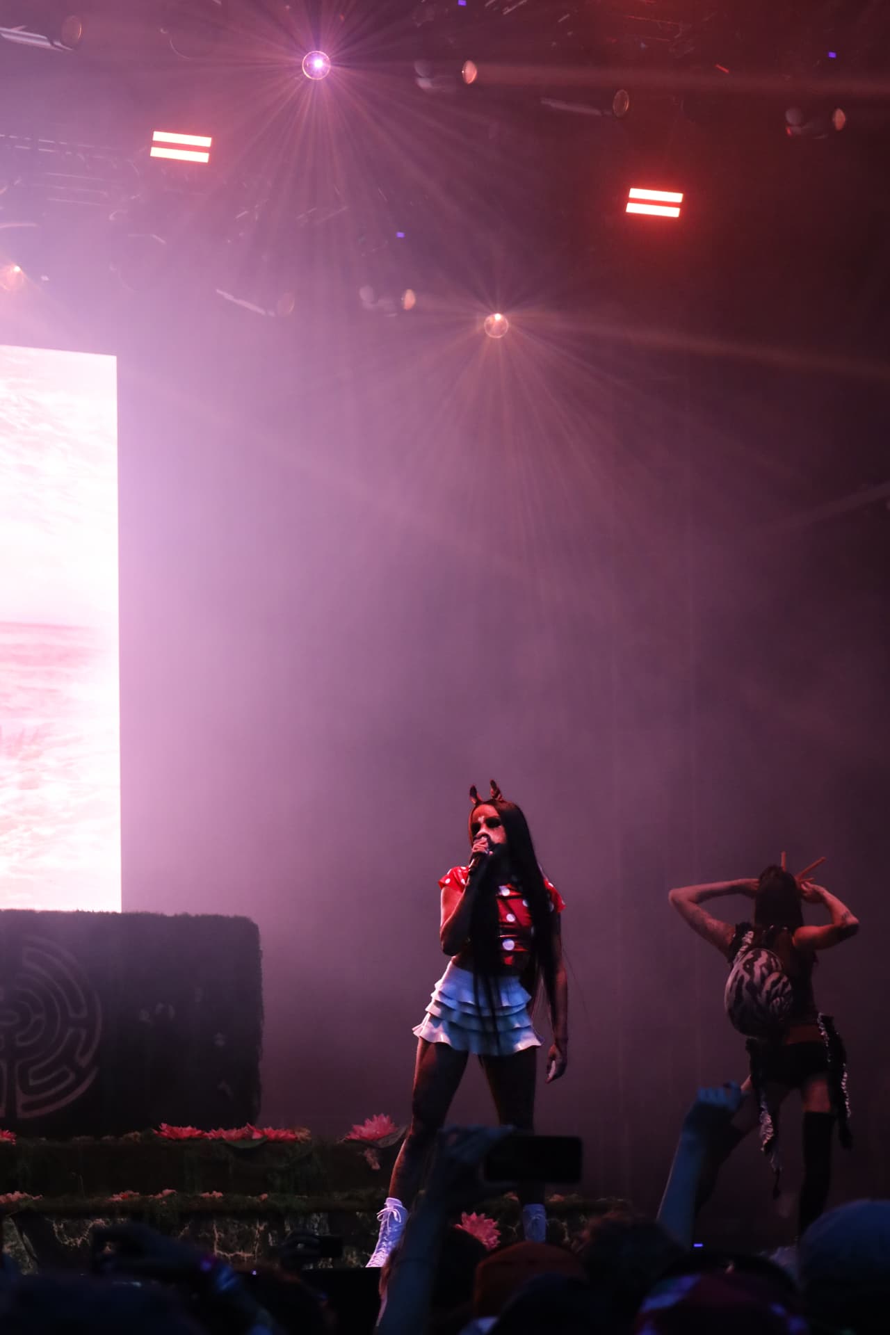 Singer performing in pink stage haze with lens flares overhead