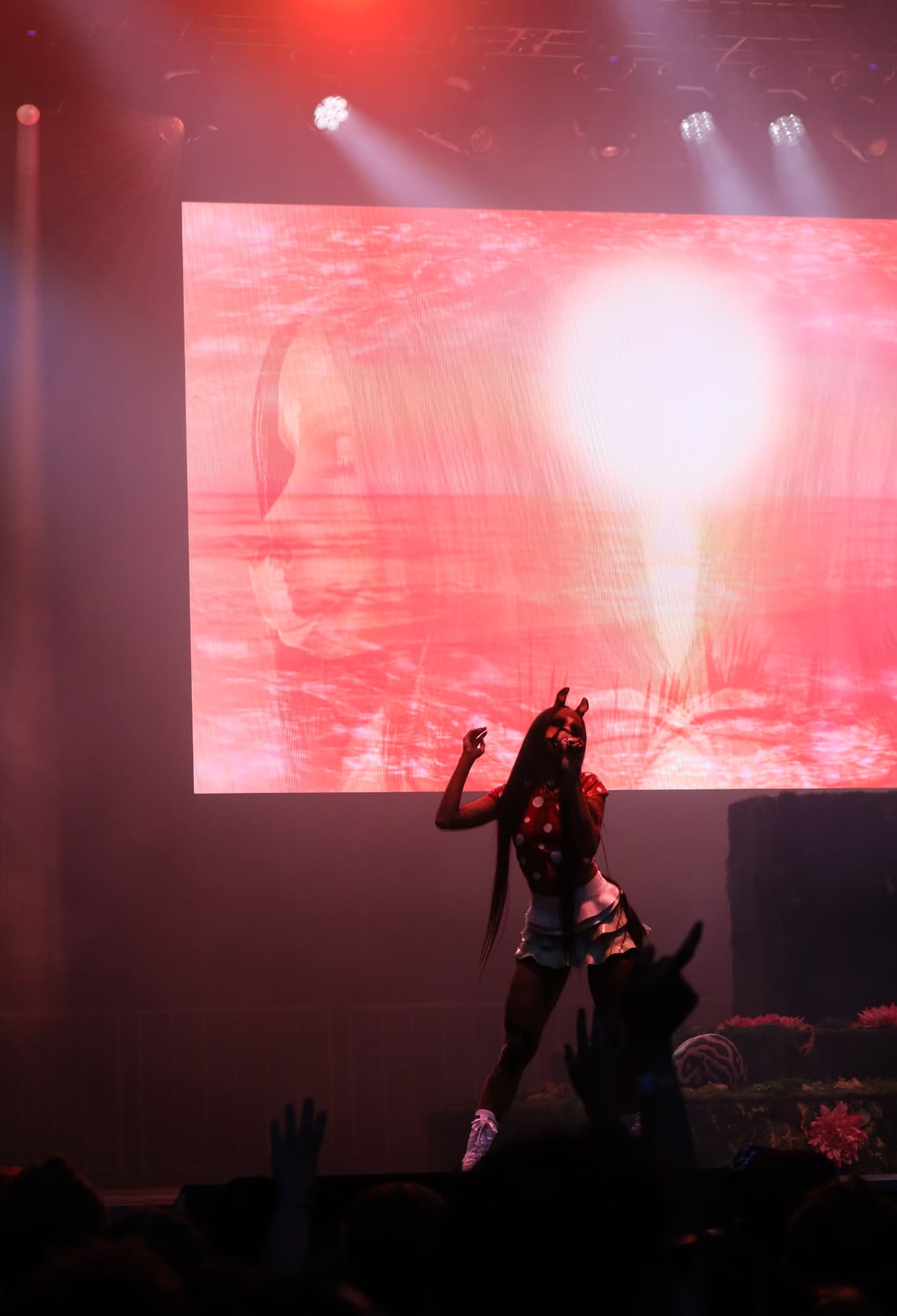 Silhouetted vocalist against a glowing red stage screen