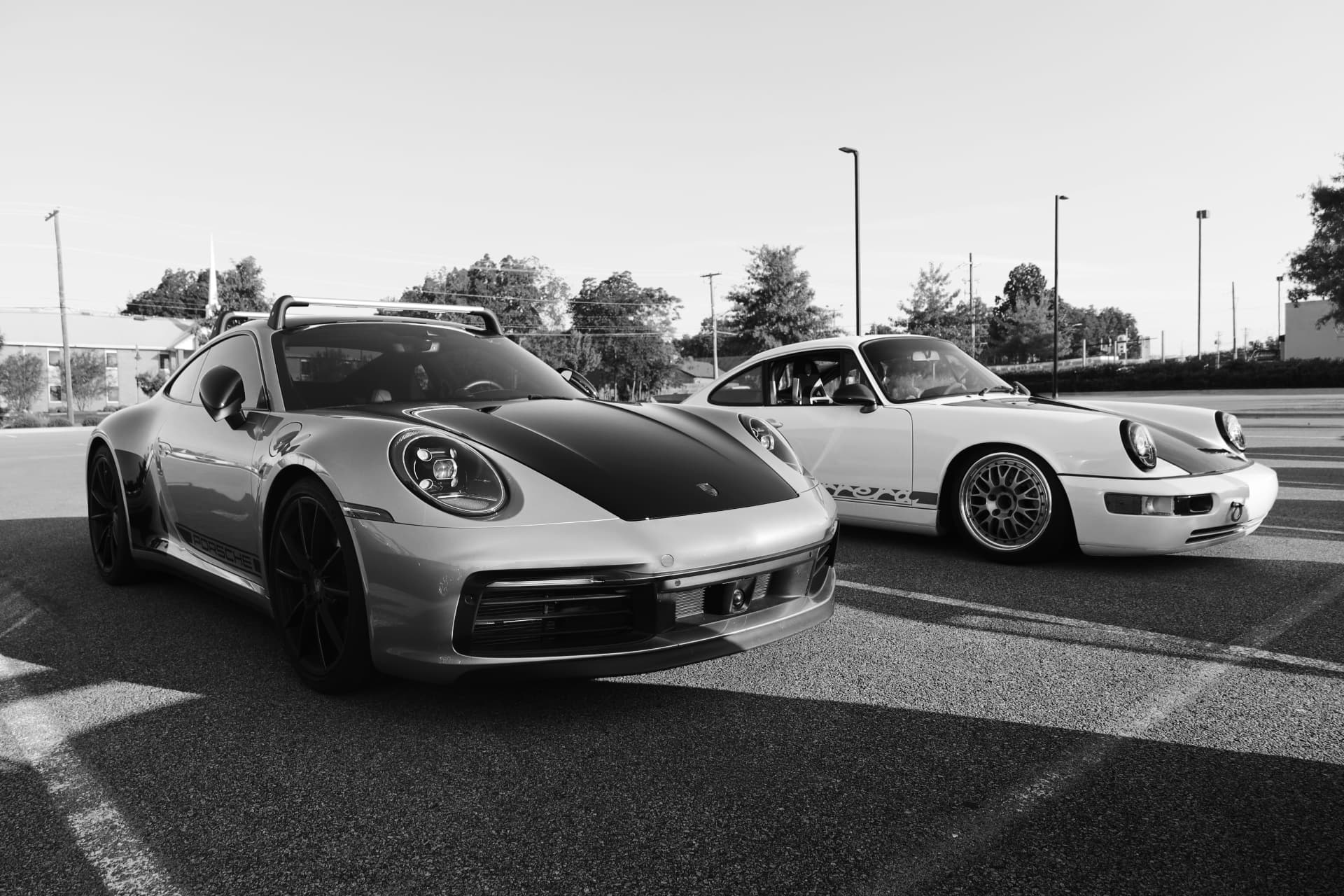 Black and white duo of modern and classic Porsche 911s in a parking lot