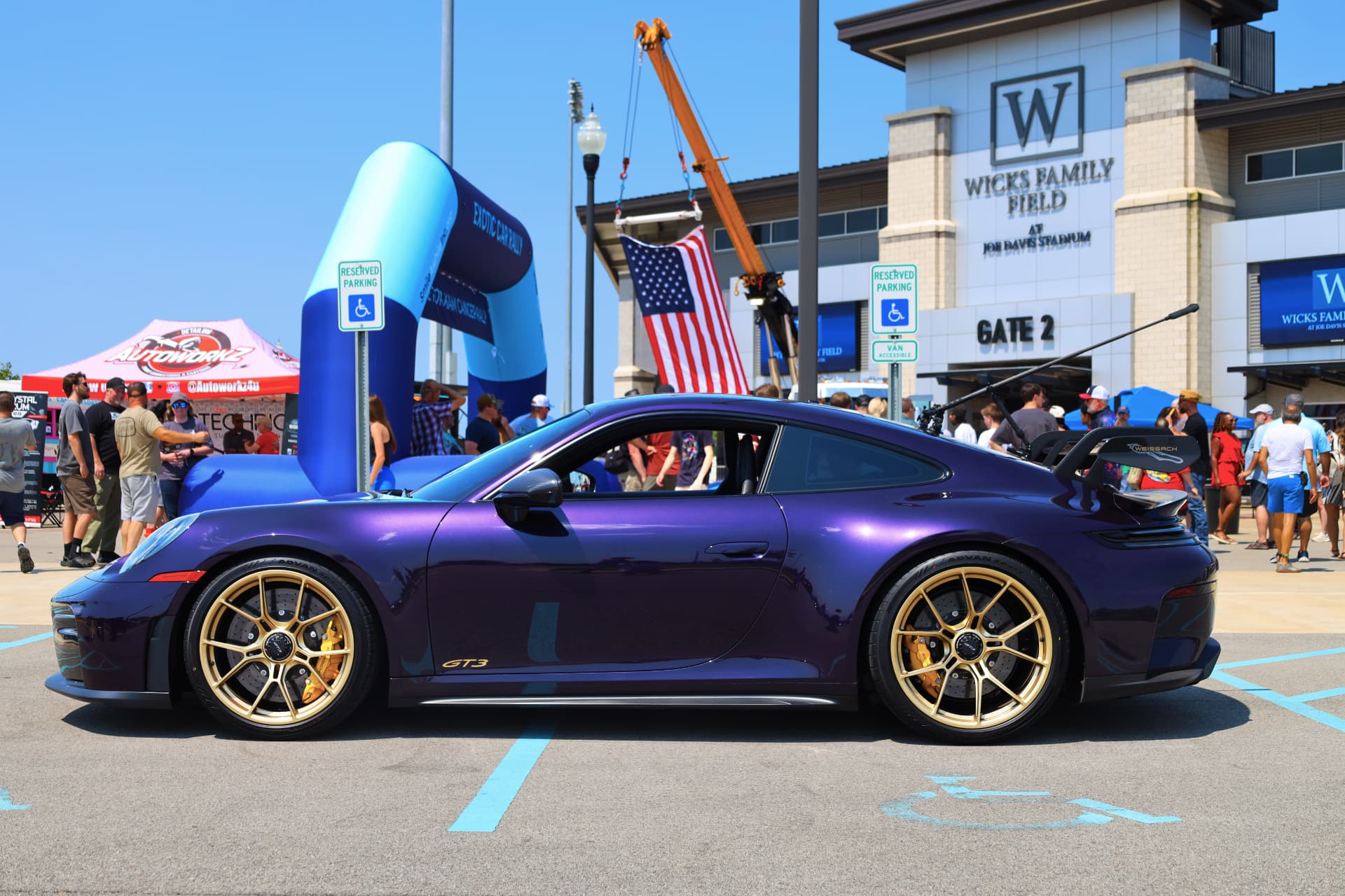 Purple Porsche 911 GT3 with gold wheels at an exotic car show