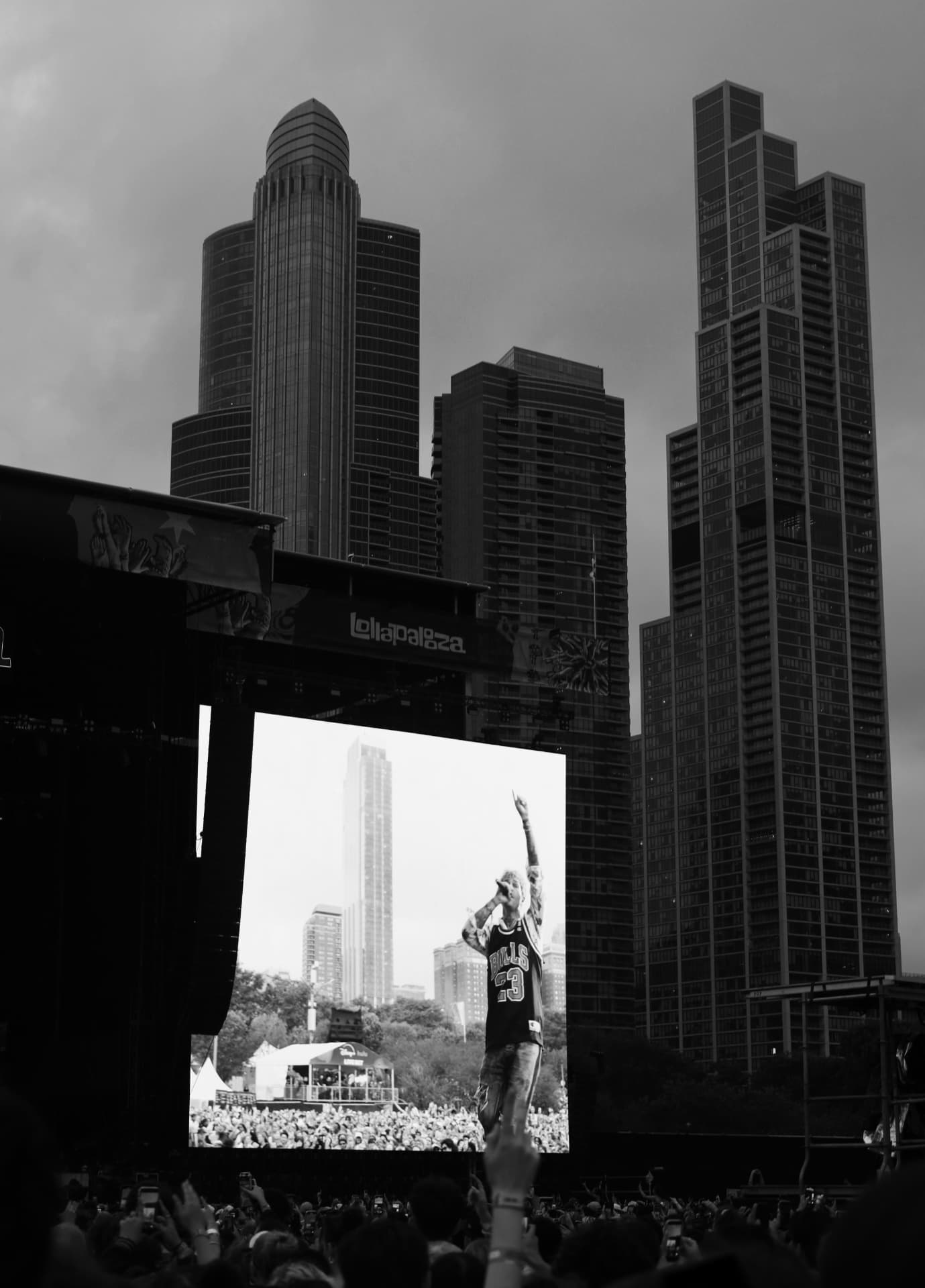 Black and white Lollapalooza stage screen and Chicago skyline above the crowd