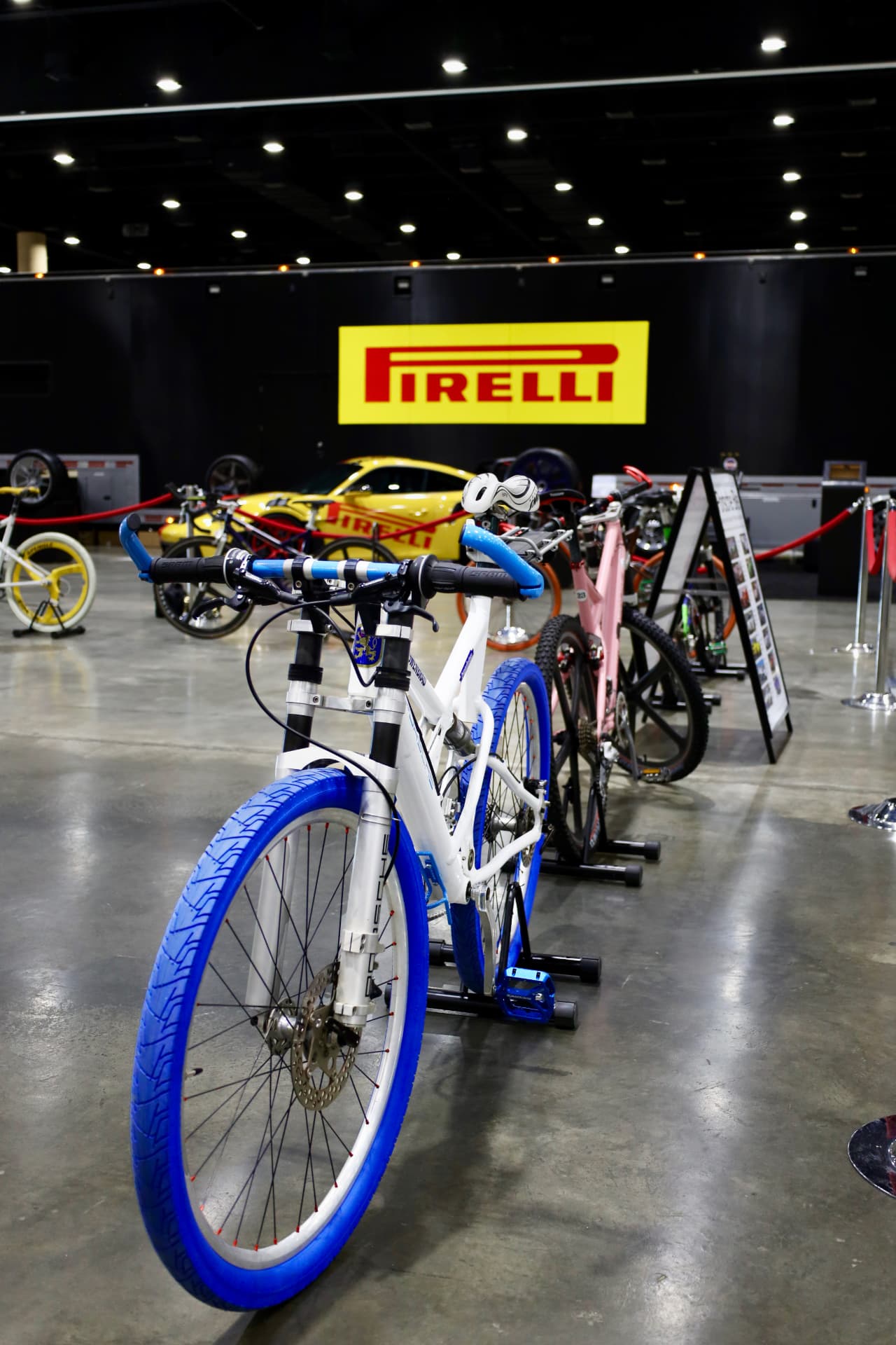 Row of custom bicycles displayed beneath a Pirelli sign at an indoor expo