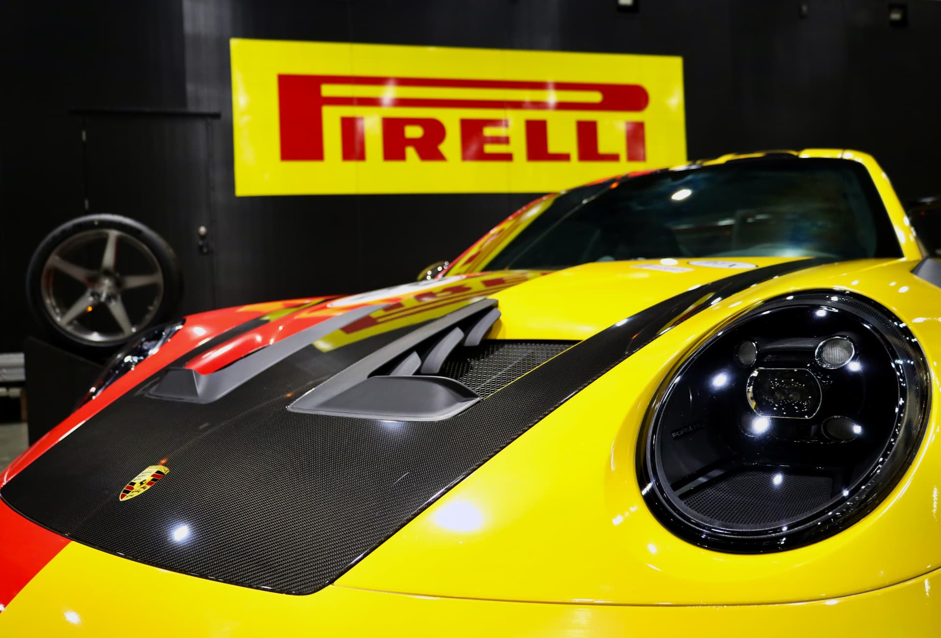 Close detail of a yellow Porsche race car hood in front of a Pirelli sign