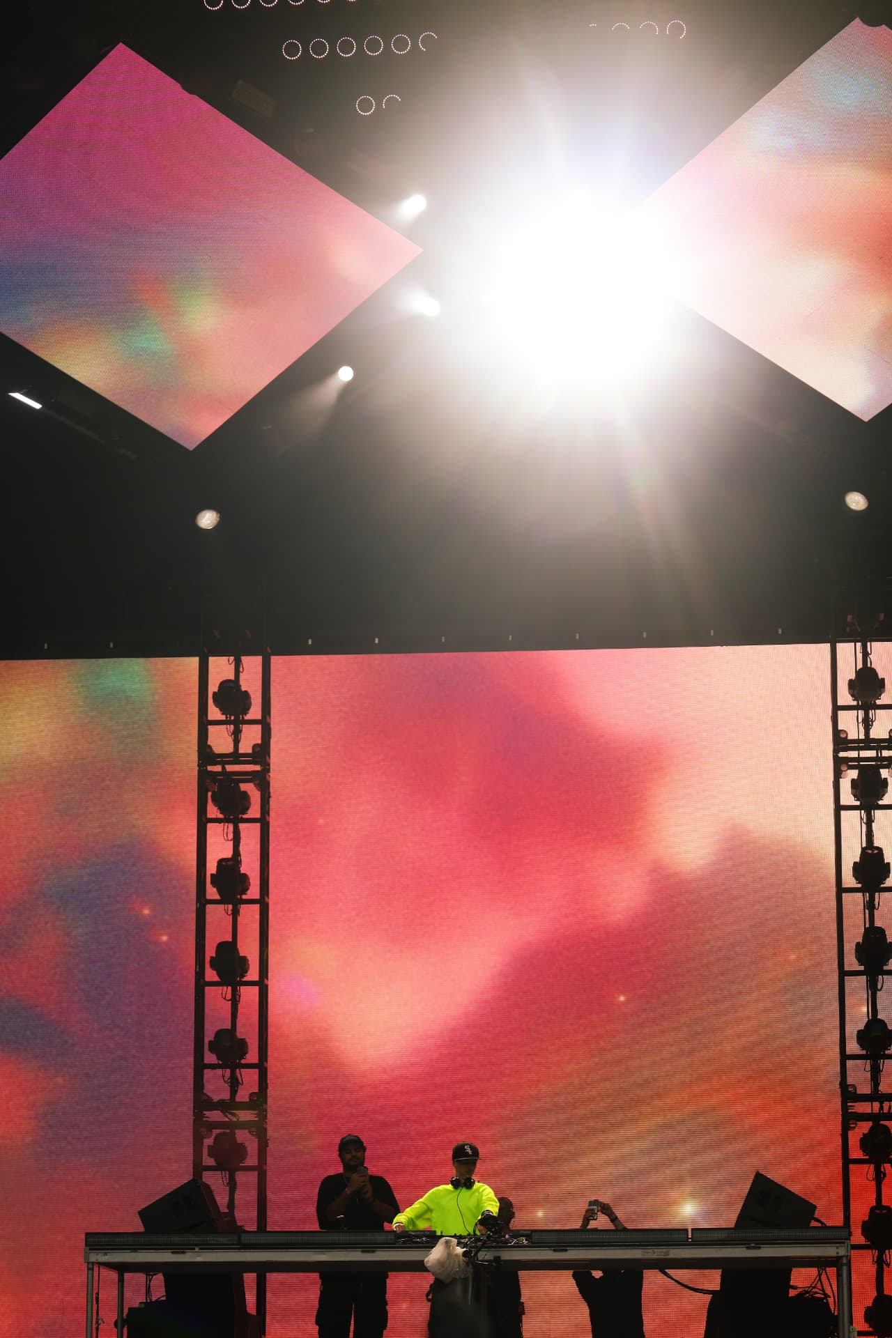 DJ on stage against a warm sunset sky backdrop with diamond screens